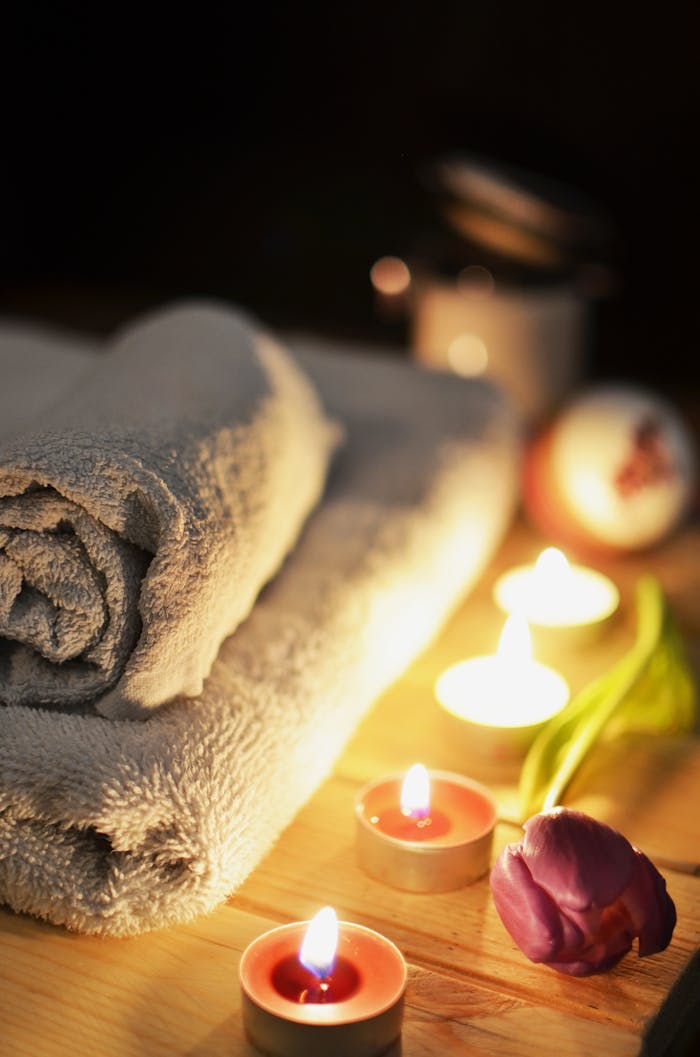 about-us-02 Relaxing spa atmosphere with candles, towels, and a tulip, perfect for wellness and self-care.
