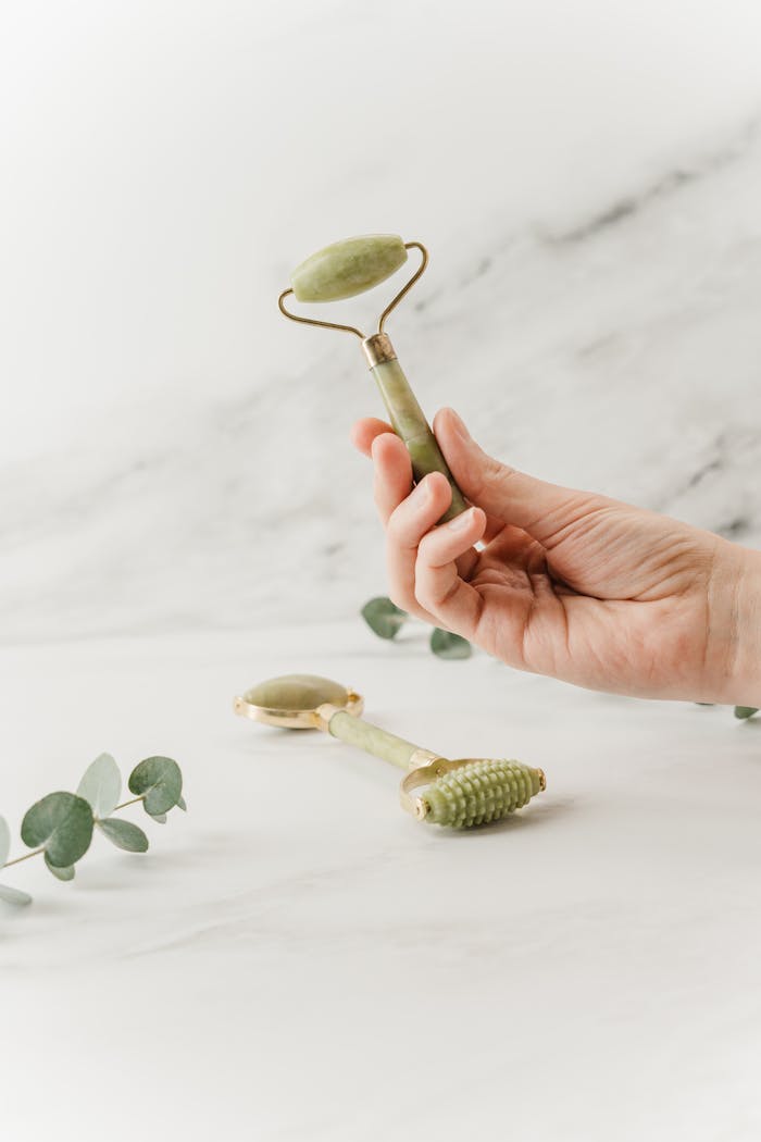 Hand holding a jade roller for skincare and self-care in a spa setting.